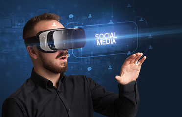 Businessman looking through Virtual Reality glasses with SOCIAL MEDIA inscription, social networking concept