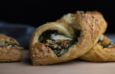 Puff pastry with spinach and cheese lying on a wooden table closeup shot