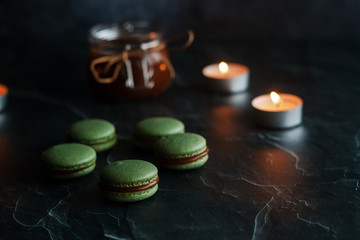 Macaroons. Delicious french dessert. Romantic composition with a jar of caramel and candles