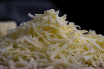 Close up of grated yellow cheese against dark background