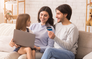Modern Family With Little Daughter Using Laptop Computer And Credit Card