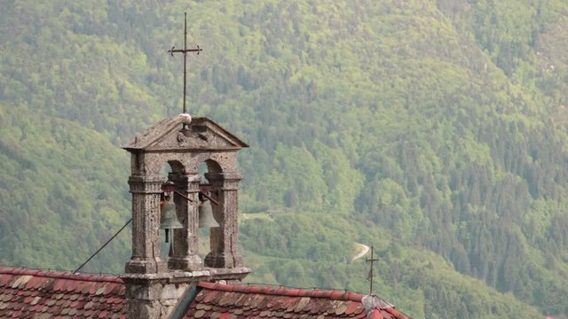 church bells on green background, the religious building is situated in Zuglio, Italy.