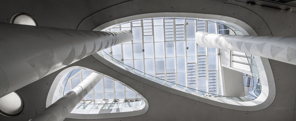 Super wide angle of a white atrium with skylight taken from below with columns that extend upwards - obrazy, fototapety, plakaty