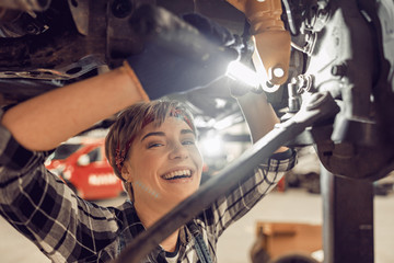 Attractive female standing under the raised car