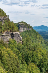 Fototapeta na wymiar Pravcicka brana in Bohemian Switzerland. Prebischtor Gate mountain view. Narrow rock, largest natural sandstone arch in Europe. Hill scenery with greenery, blue sky and sunlight, natural environment.