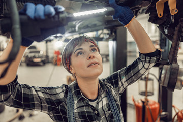 Mechanic holding a flashlight above her head - obrazy, fototapety, plakaty