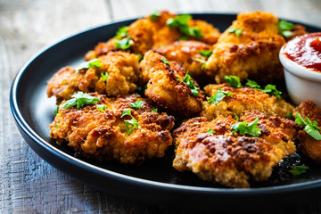 Fried chicken nuggets with ketchup on wooden table