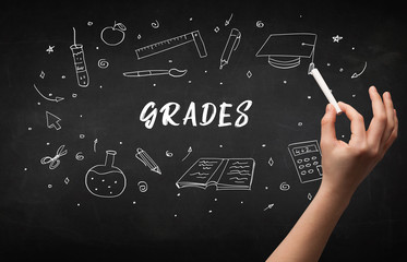 Hand drawing GRADES inscription with white chalk on blackboard, education concept