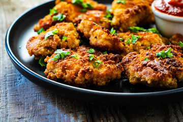 Fried chicken nuggets with ketchup on wooden table