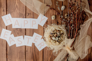 Flat lay composition of quail eggs and card with text Happy Easter on wooden table. Top view.