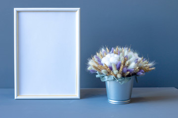 composition of dried flowers and a white photo frame on a gray background copy space