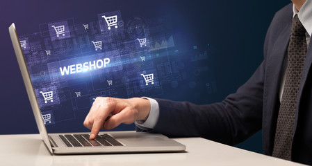 Fototapeta na wymiar Businessman working on laptop with WEBSHOP inscription, online shopping concept