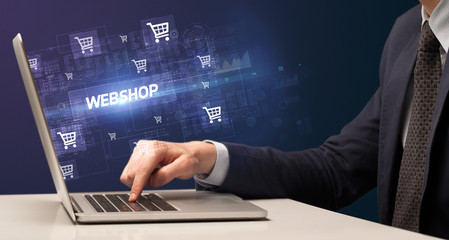Fototapeta premium Businessman working on laptop with WEBSHOP inscription, online shopping concept