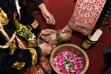 Injak Telur Ceremony in Javanese wedding. Groom breaks an egg using foot, signifies that he's ready to be a responsible head of family. The bride washes groom's foot as symbol of support and loyalty