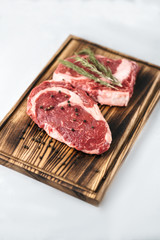 Raw meat beef steak, with ingredients for cooking on a wooden board and white background. Top view