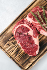 Raw meat beef steak, with ingredients for cooking on a wooden board and white background. Top view
