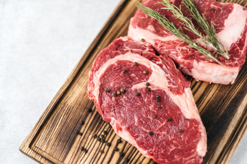 Raw meat beef steak, with ingredients for cooking on a wooden board and white background. Top view