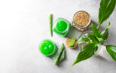 Fresh aloe vera gel in a glass jar with aloe on a light background.