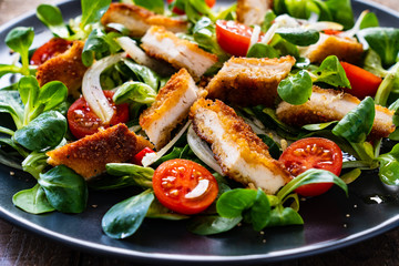 Fried chicken breast and vegetables on wooden table