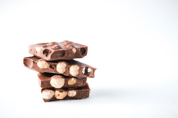 Pieces of dark chocolate with nuts in the form of a tower on a white background.