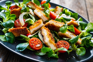 Fried chicken breast and vegetables on wooden table