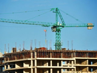 Fototapeta na wymiar Construction crane near the building under construction. Concrete building under construction. Construction site.