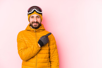 Young skier man isolated smiling and pointing aside, showing something at blank space.