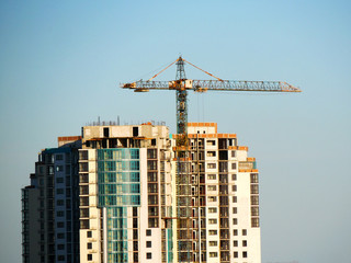 Fototapeta na wymiar Construction site background. Self-erecting crane near the building under construction. Industrial background.