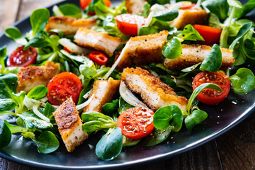 Fried chicken breast and vegetables on wooden table