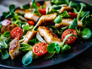 Fried chicken breast and vegetables on wooden table