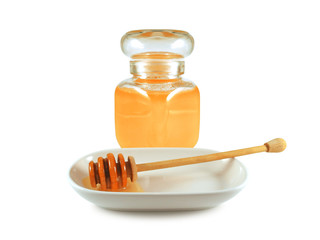 Honey in glass jar and wooden stick in porcelain plate isolated on white background. Beauty treatment and healthy food concept.
