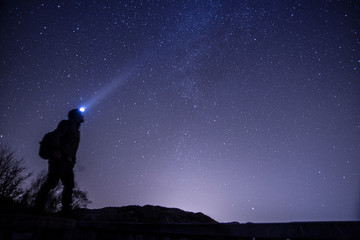 Fototapeta na wymiar Man with headlight looking up to the sky under the night stars 