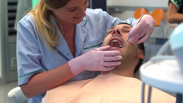 Female dental doctor with a ginger hair is examing her patient