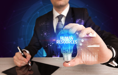 Businessman holding lightbulb with HUMAN RESOURCES inscription, Business idea concept