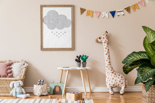 Stylish and beige scandinavian interior of kid room with mock up poster frame, design furnitures, natural toys, hanging colorful flags, plush animal, child accessories and teddy bears. Home decor.