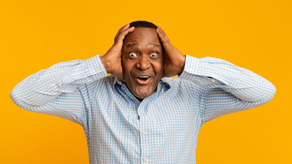 Portrait of excited mature african man holding his head
