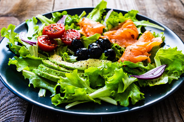 Salmon salad - smoked salmon and vegetables on black stone background