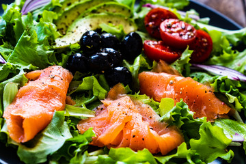Salmon salad - smoked salmon and vegetables on black stone background