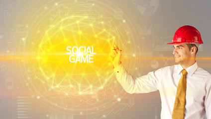 Handsome businessman with helmet drawing SOCIAL GAME inscription, social construction concept