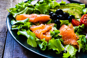 Salmon salad - smoked salmon and vegetables on black stone background