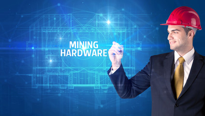 Handsome architect with helmet drawing MINING HARDWARE inscription, new technology concept