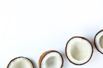 Top view shot of coconuts cracked on halves on paper textured background with a lot of copy space for text. Bacground with raw fruit of tropical palm. Flat lay.