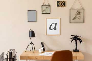 Design scandinavian interior of home office space with a lot of mock up photo frames, wooden desk, brown chair, table lamp, office and personal accessories. Stylish neutral home decor. Template.