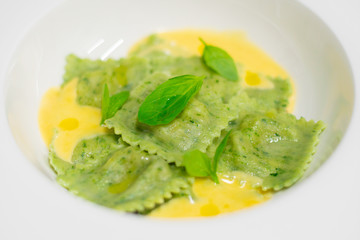 Ravioli pasta made from green dough with cheese sauce