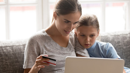 Head shot portrait concentrated young mom with daughter online shopping.