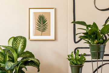 Retro interior design of living room with a lot of plants in green pots, vintage decor, accessoreis and gold mock up picture frame on the beige wall. Minimalistic concept of home decor. Template  © FollowTheFlow