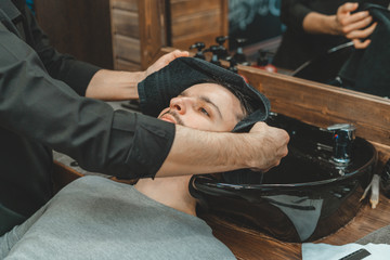 Barbershop, a man is washed his hair. Barber washes his client. Wash hair and beards after cutting. Personal care