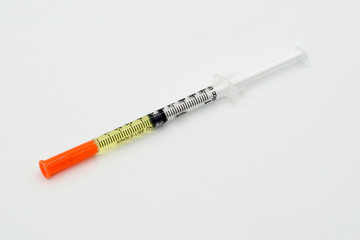 Fototapeta premium An insulin syringe with a yellow medicine lies on a white background