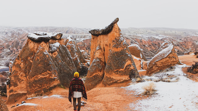 Woman alone with snowy landscape at Devrent Valley in Cappadocia. Girl walking around Fairy chimneys surronded by snow in Imaginary Valley in winter season in Cappadocia.