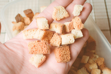 Baked sliced white bread crackers on man hand.